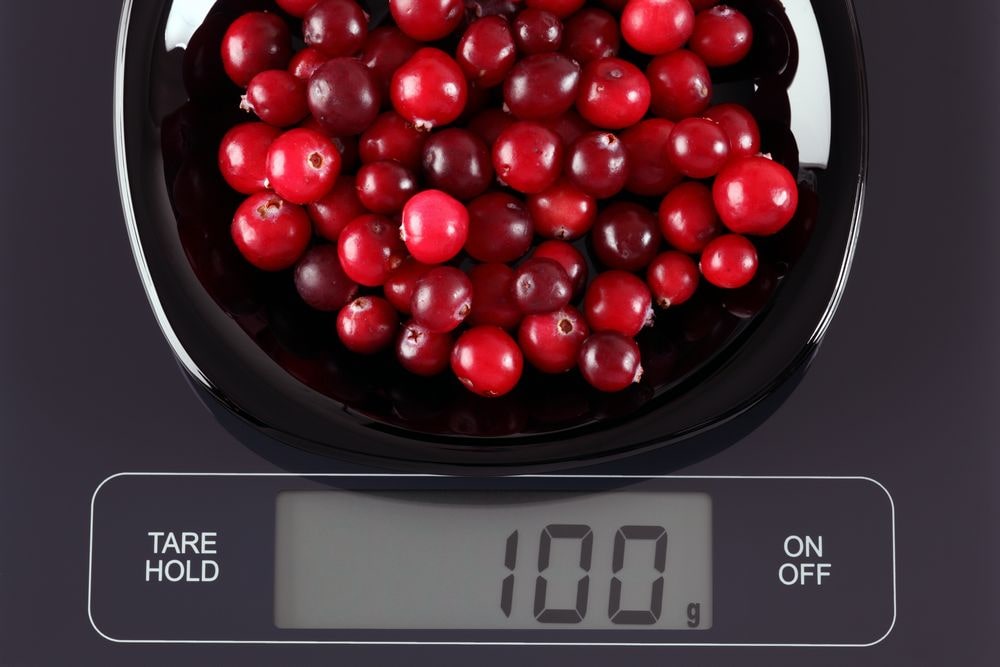 A diet scale with the serving of fresh cranberries.