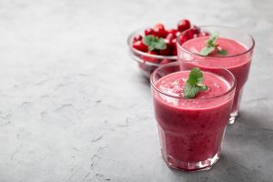 A delicious looking glass with fresh cranberry and other food ingredients and a refreshing drink.