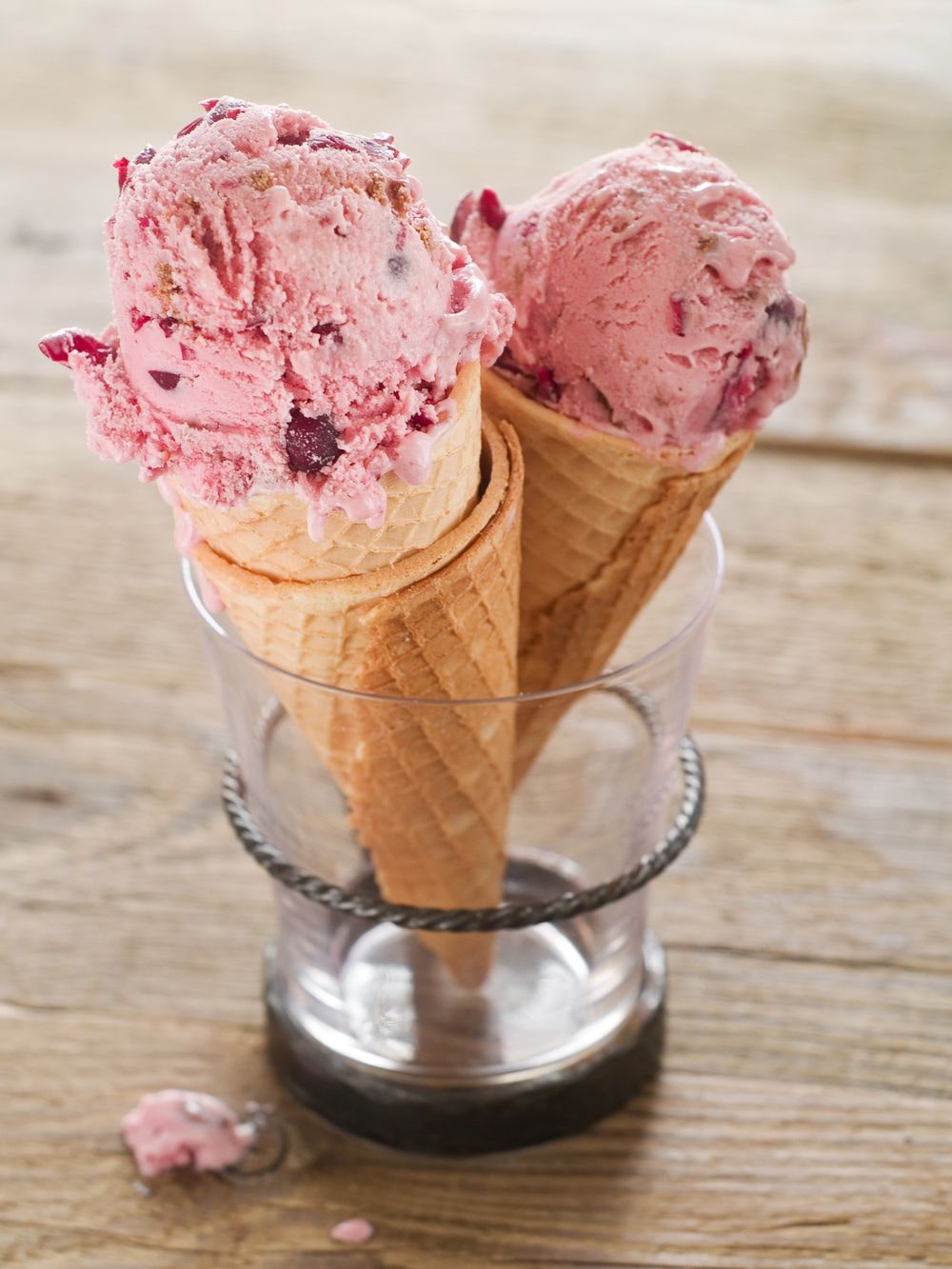Homemade scoops of ice cream made with cranberries in cones.