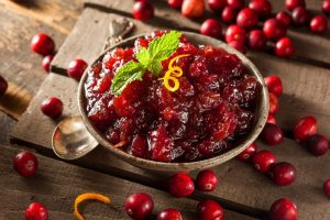 A bowl of homemade cranberry sauce with a slice of orange zest.