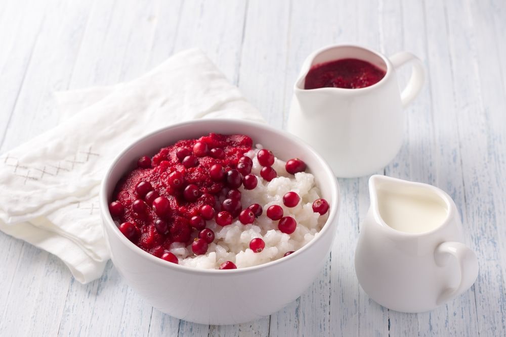 A bowl of tasty rice pudding with cranberry jam or sauce on top.