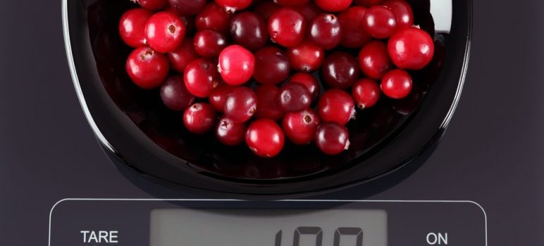 A diet scale with the serving of fresh cranberries.