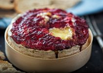 Cranberries turn to cranberry sauce atop this wheel of baked camembert cheese.